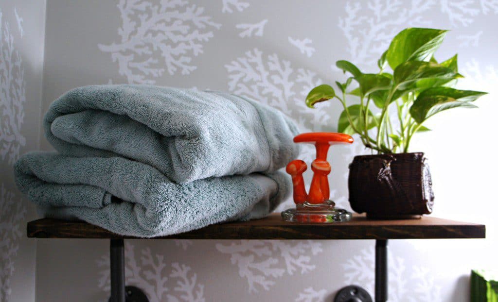 shelf with blue towel, plant, and glass mushroom statue. 