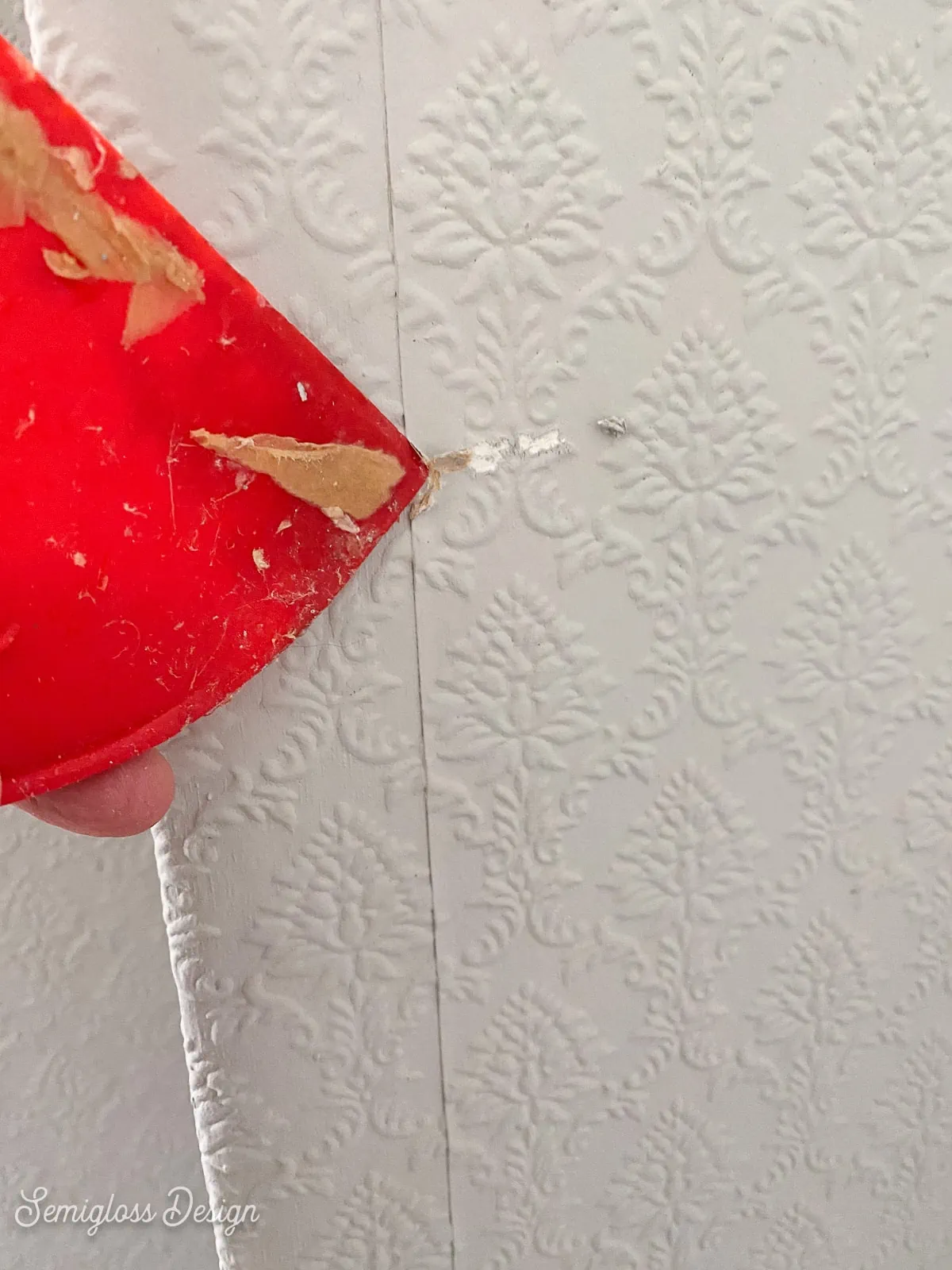 red scraper removing wallpaper