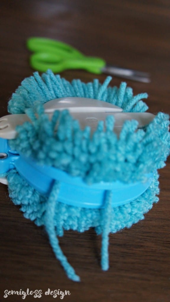 Tie yarn around pom pom maker