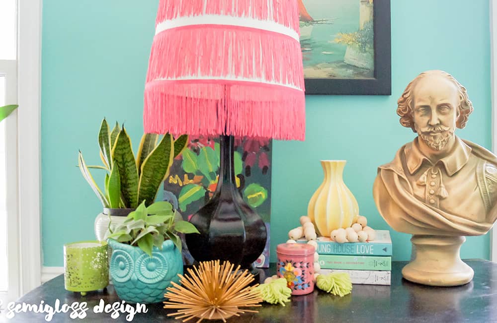 colorful vignette with pink fringe lampshade, plants, and bust