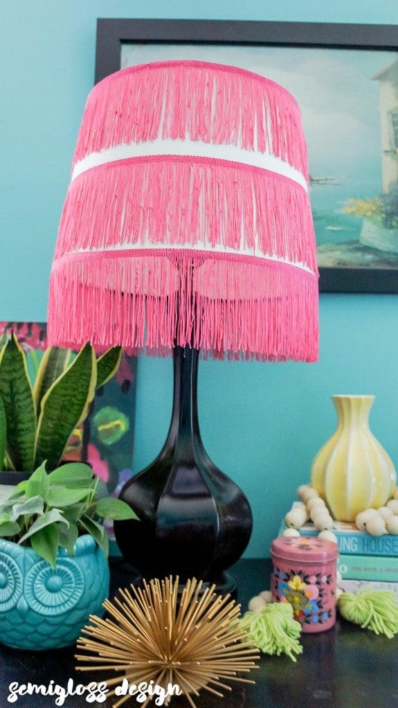 lampshade with hot pink fringe against teal wall