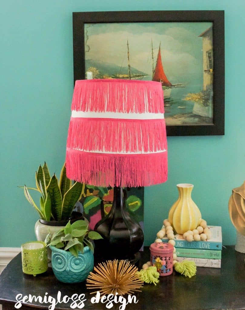 pink fringe lampshade with plant on dresser