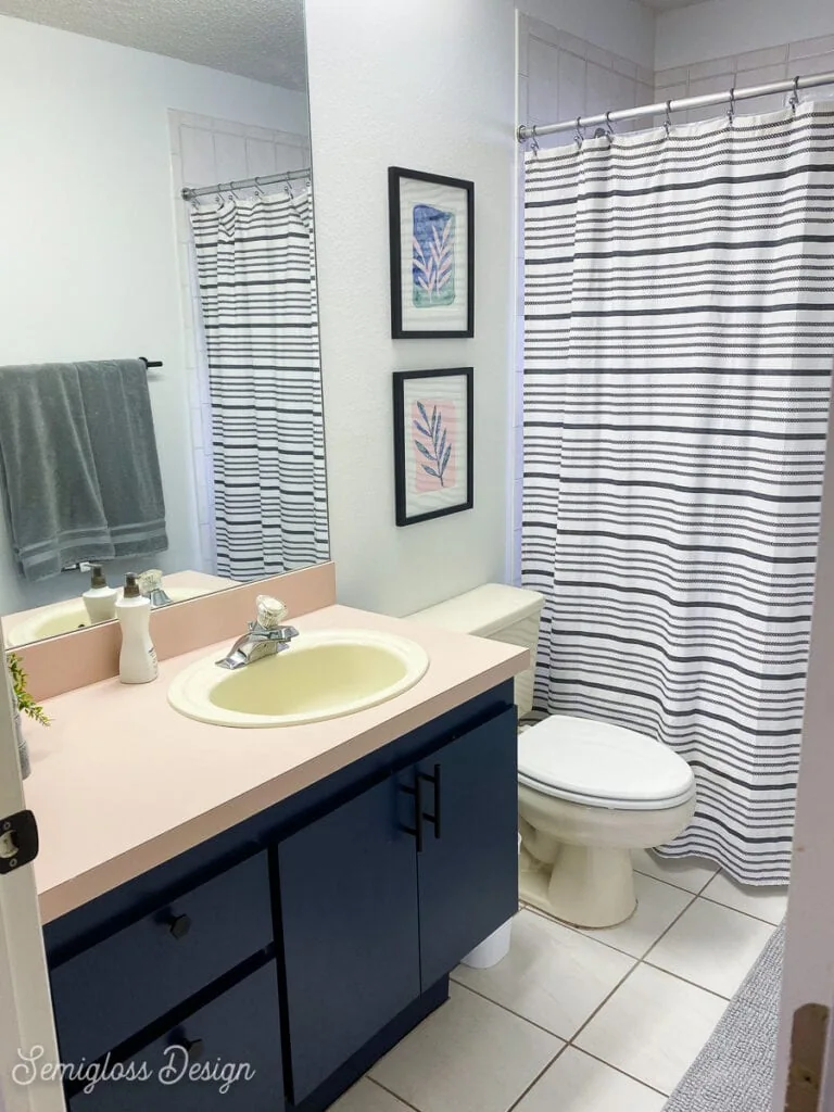 bathroom with pink counter and striped shower curtain