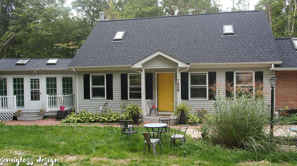 cape cod home with yellow front door and black shutters