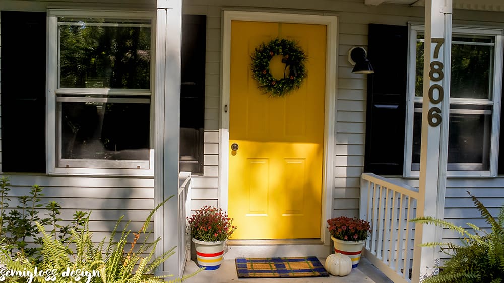 yellow painted front door with wreath