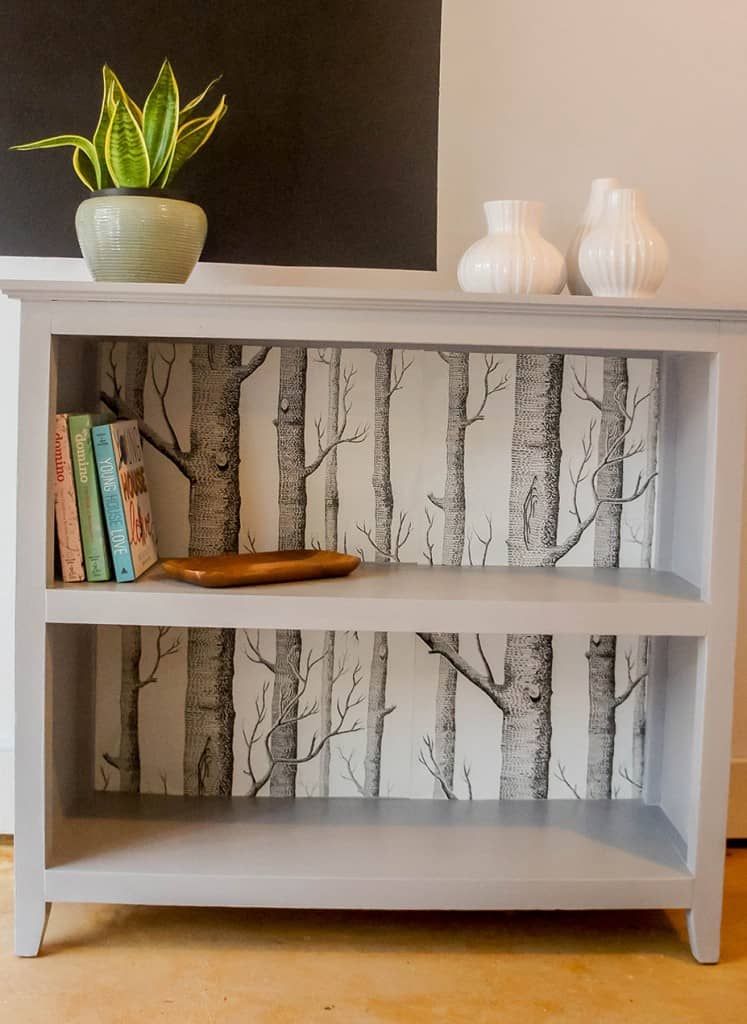 Painted bookcase with tree wallpaper backing