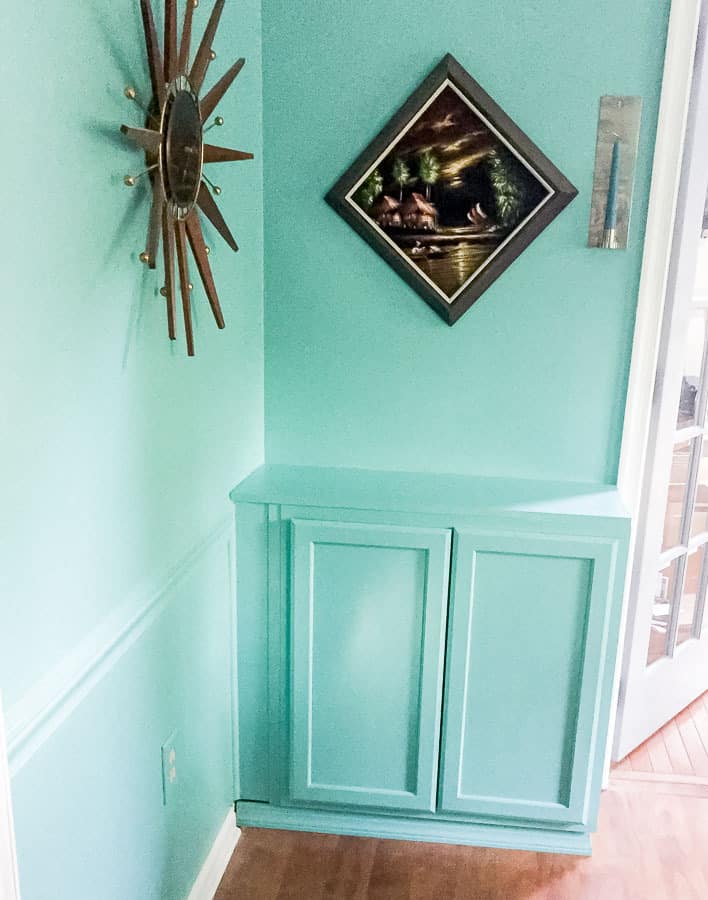 teal cabinet on wall with painting