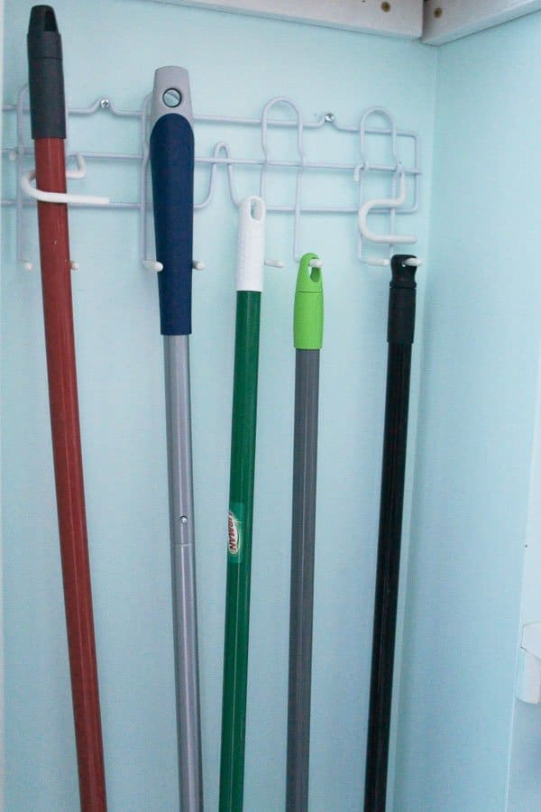 a broom holder holds brooms and mops