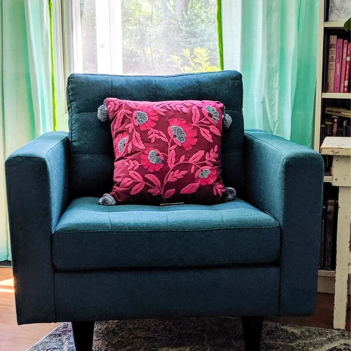 teal armchair with pink pillow