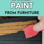 red scraper removing black paint from wood drawer
