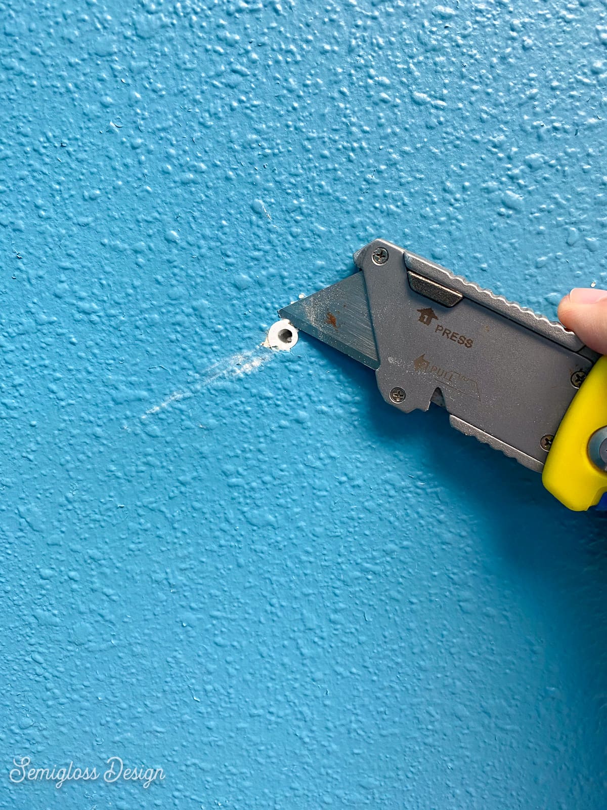 using utility knife to cut away wall anchor