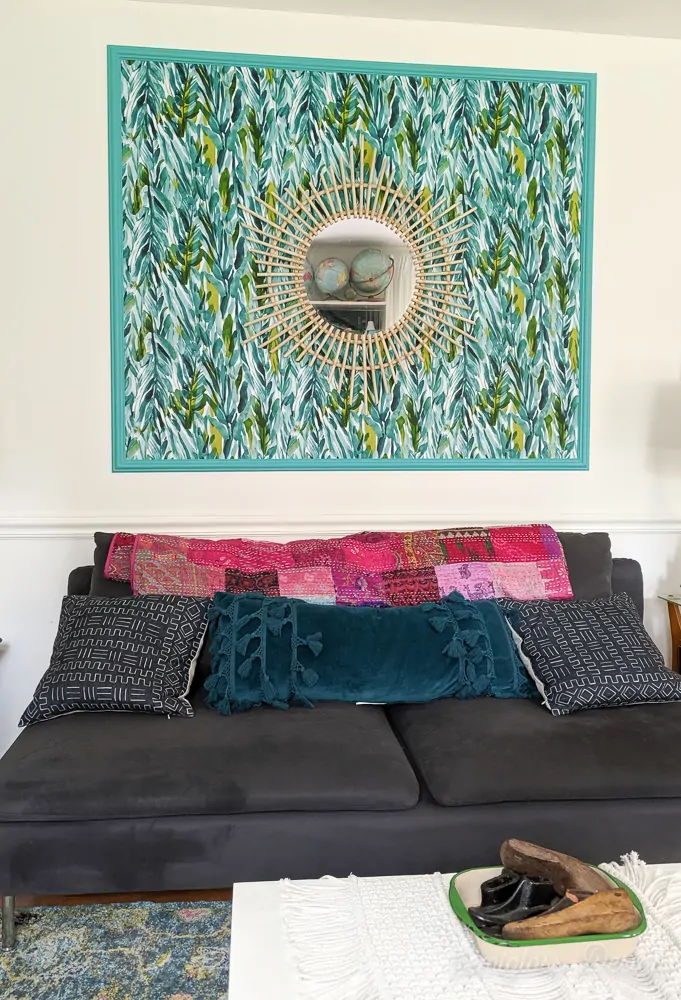 living room with teal framed wallpaper panel and boho rattan mirror