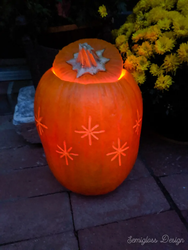 starburst etched pumpkin lit up at night