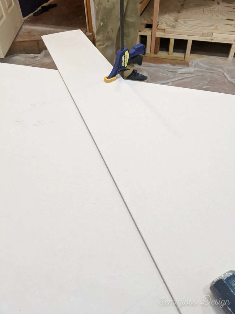 using long piece of drywall as straight edge for cutting