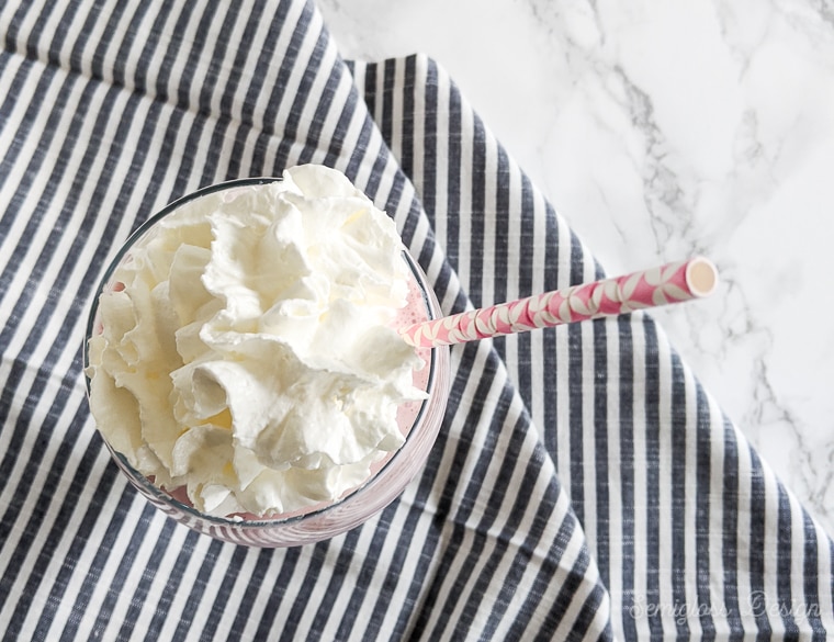 strawbeery milkshake with whipped cream on striped napkin and marble background