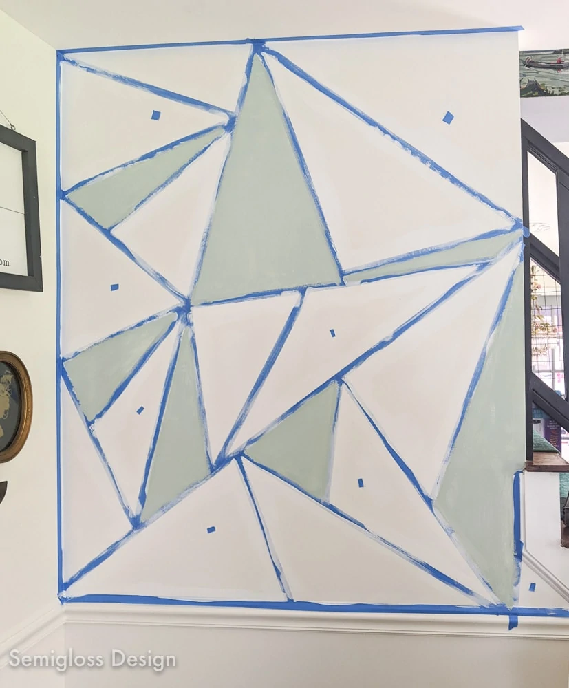 painting a pale teal color onto geometric mural