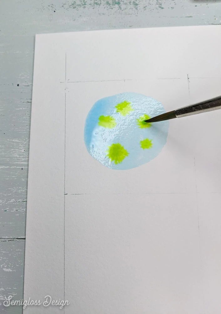 painting dots of green in blue watercolor circle