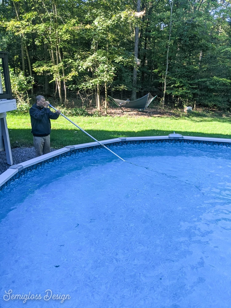 man cleaning pool with brush