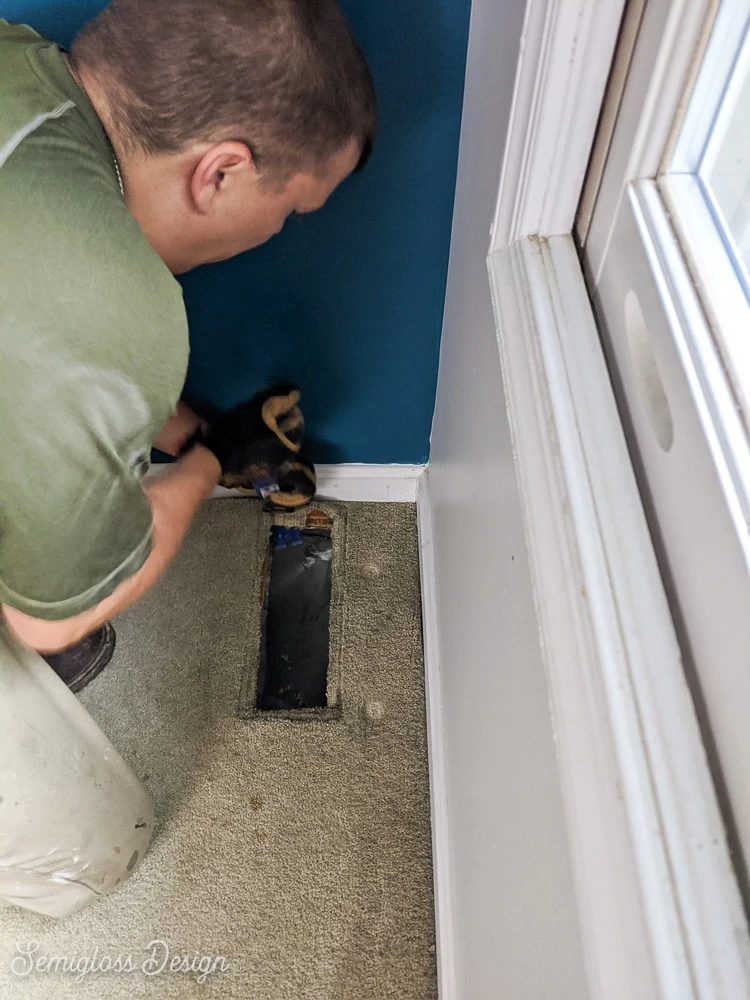 man removing carpet starting in corner of room