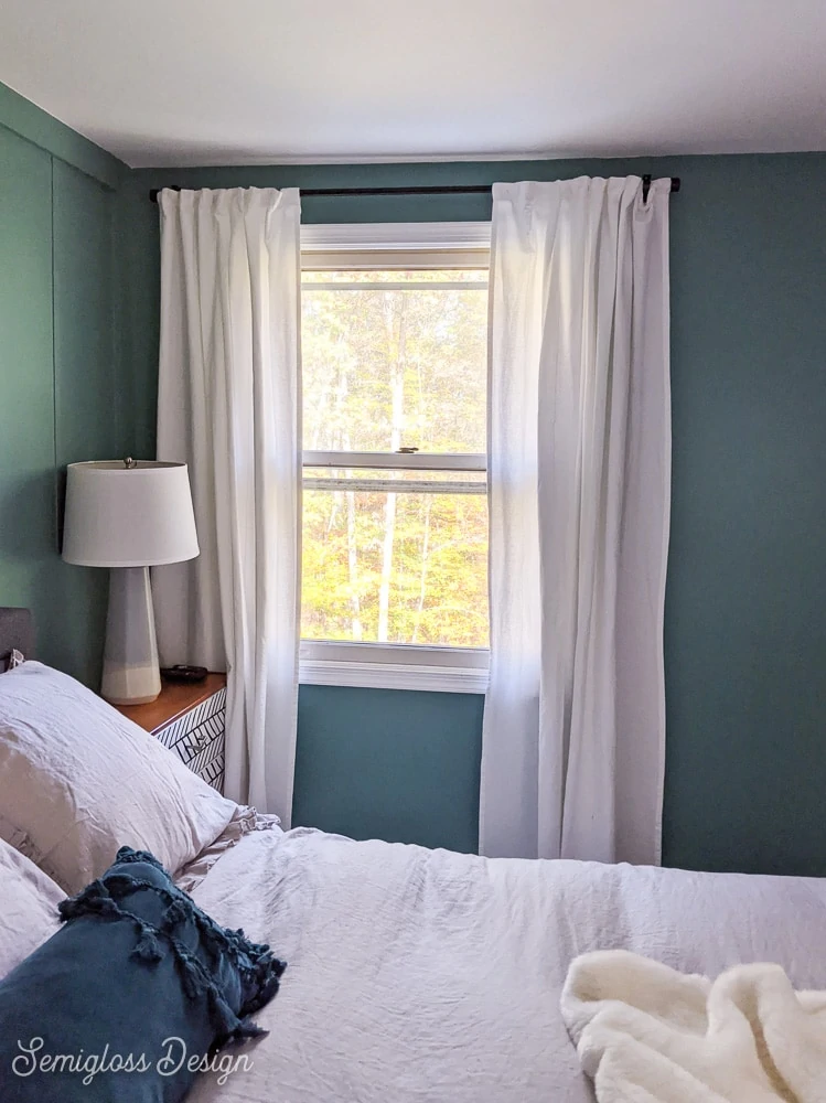 white curtains on teal walls in bedroom with bed in foreground