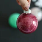 hand holding red glitter ornament