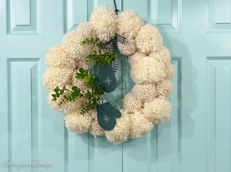 white pom pom wreath on aqua doors