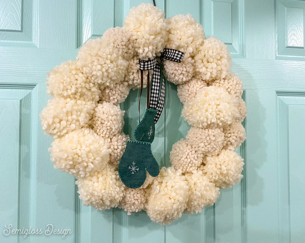 adding mittens and a bow to pom pom wreath