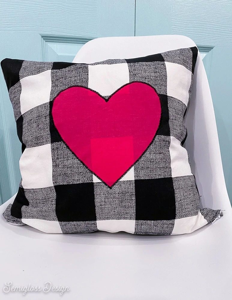 black and white buffalo check pillow with pink heart on white chair