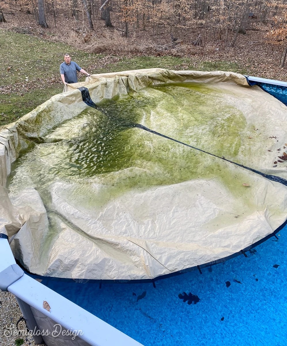 man removing pool cover form above-ground pool. 