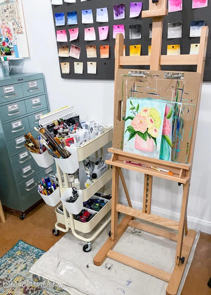 easel with flower painting and cart with paints