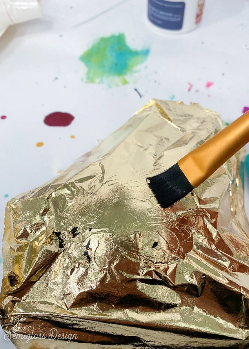 using a paintbrush to burnish gold leaf