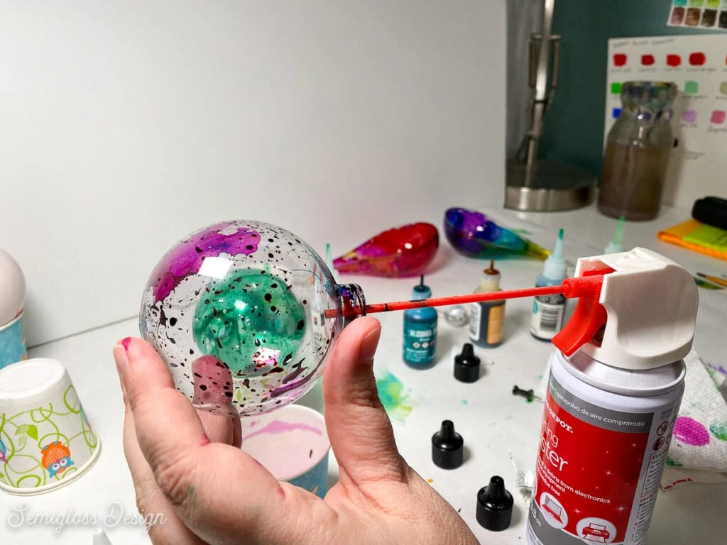 spraying alcohol ink in ornament with canned air