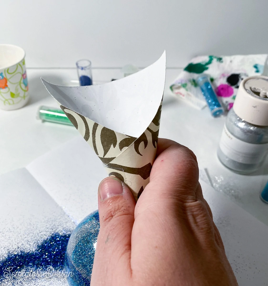 adding glitter to ornament with paper funnel