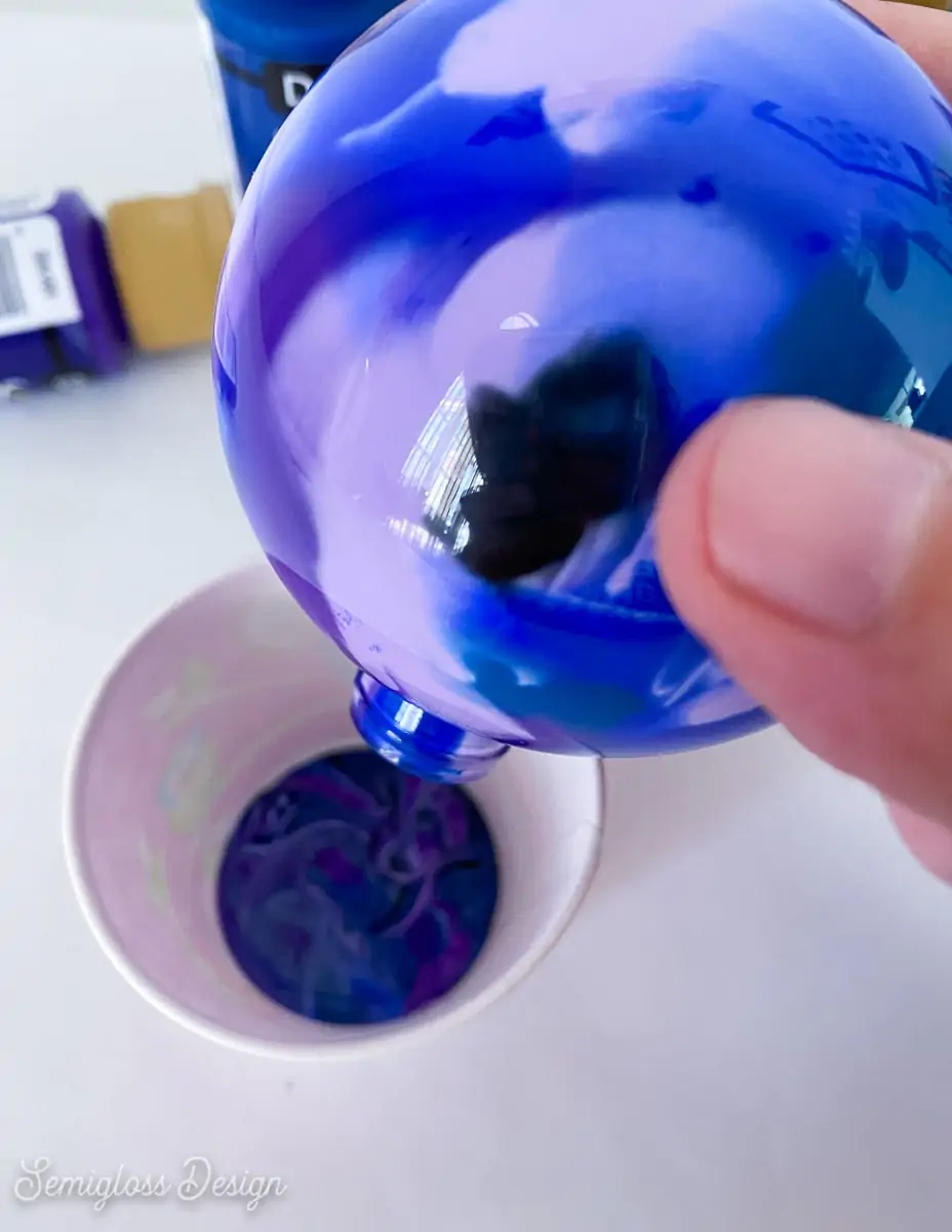 pouring excess paint out of ornament