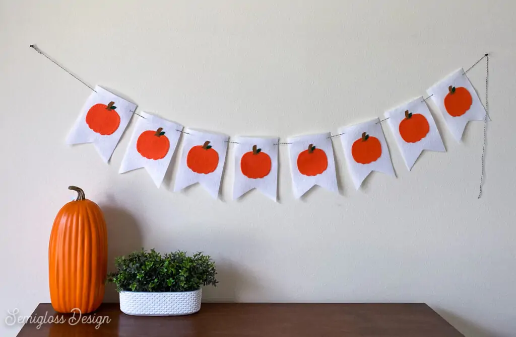 pumpkin banner hung over dresser with pumpkin and plant