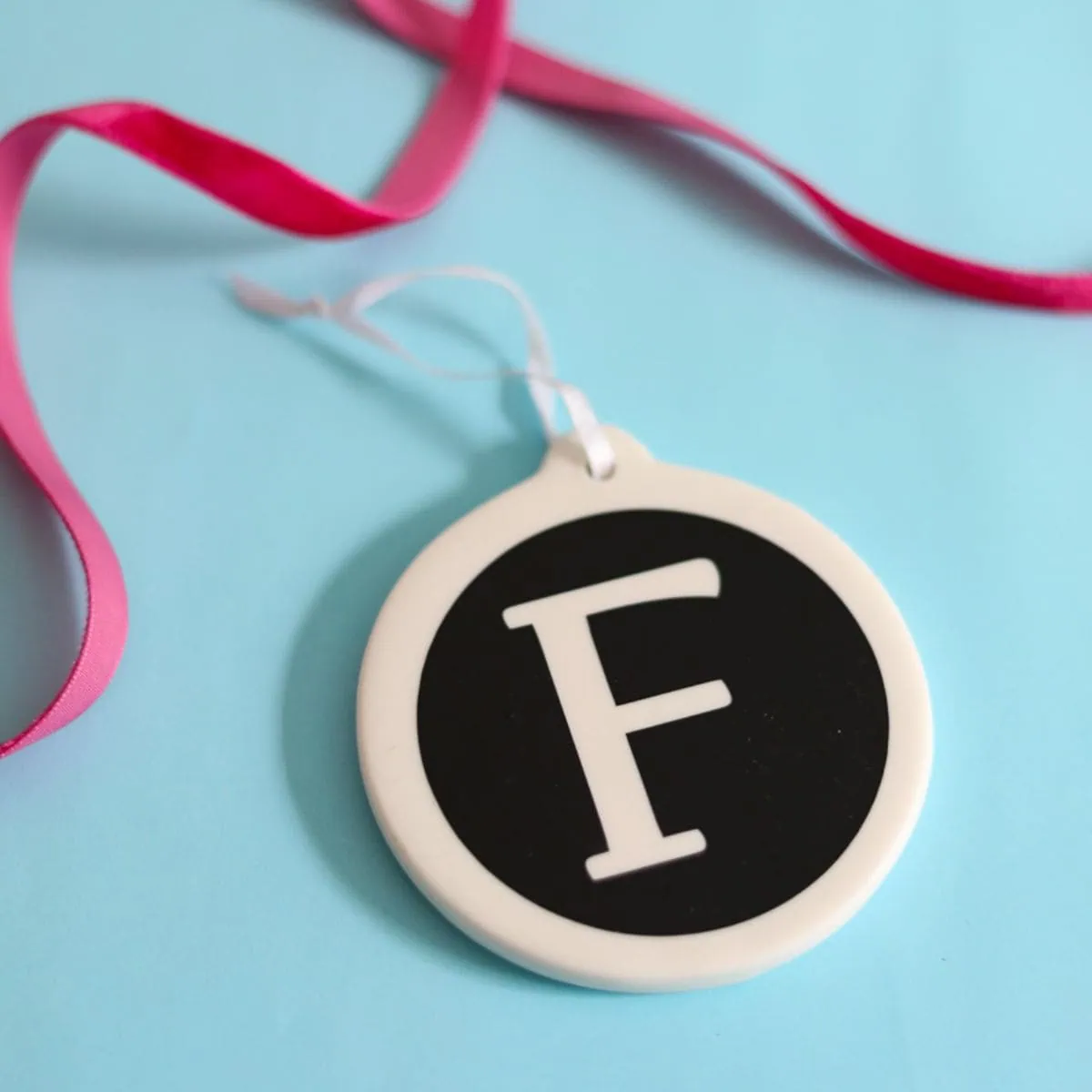 F monogram ornament on light blue background