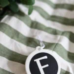 F monogram ornament on green and white striped fabric