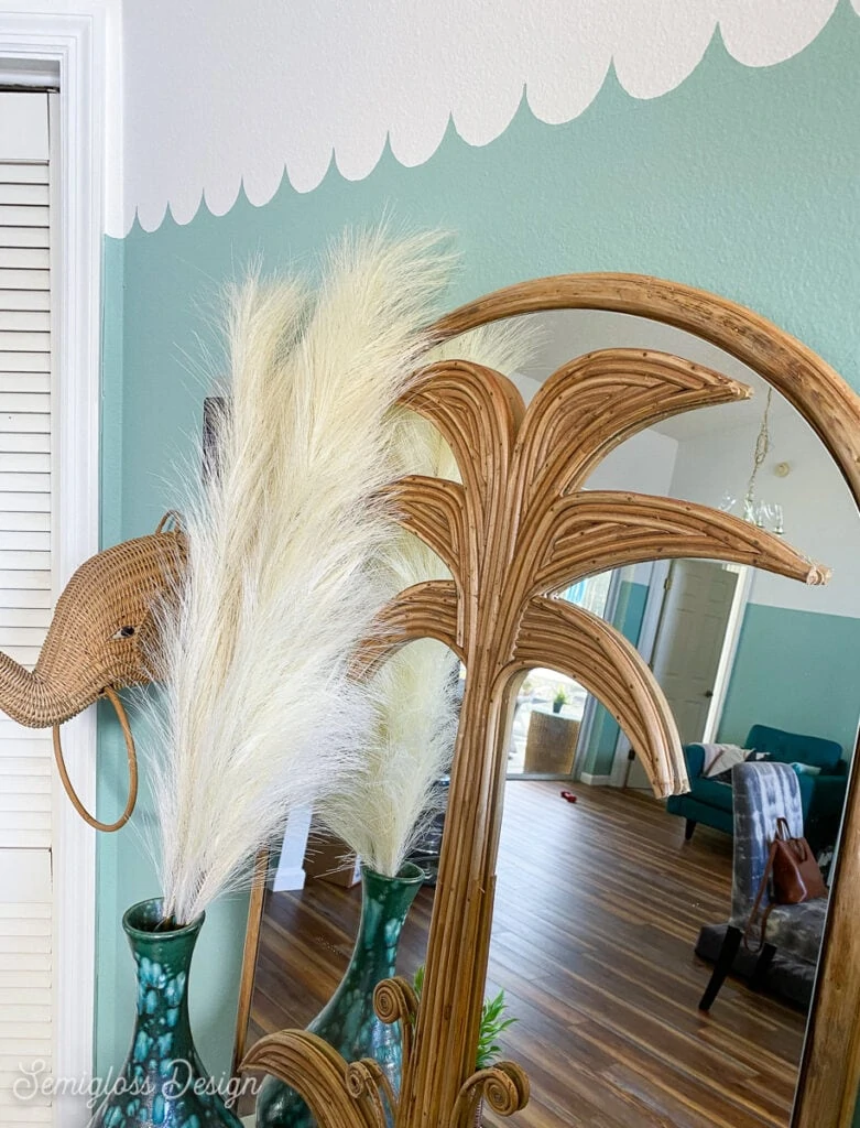 wicker elephant, pampas grass, and palm tree mirror on teal scalloped wall