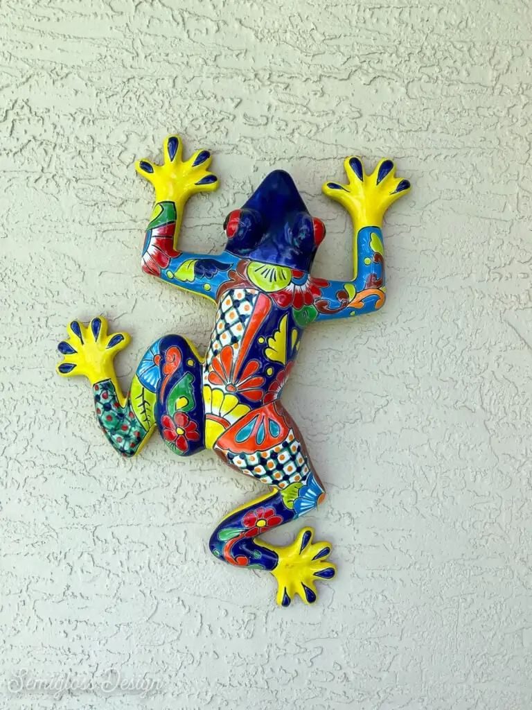 ceramic frog hanging on stucco wall on patio