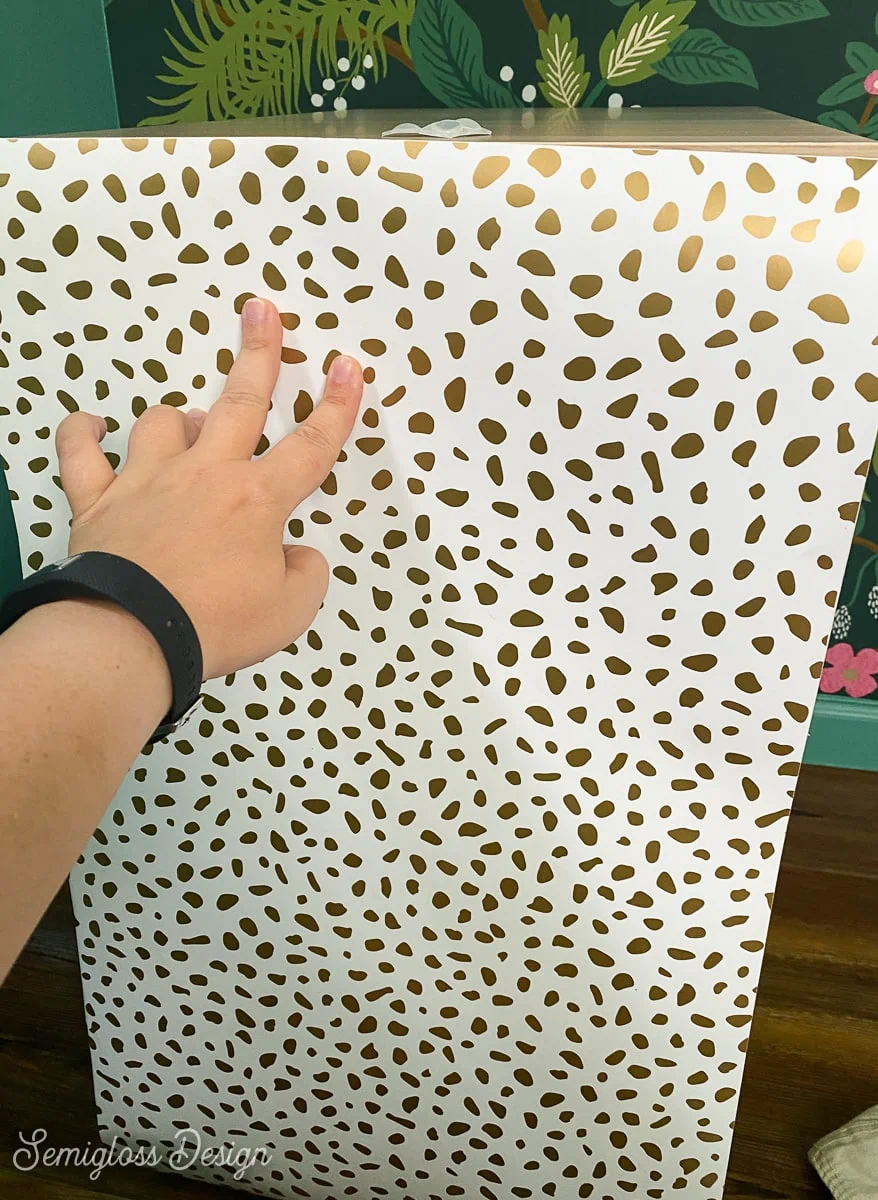 hand holding dot wallpaper to cabinet