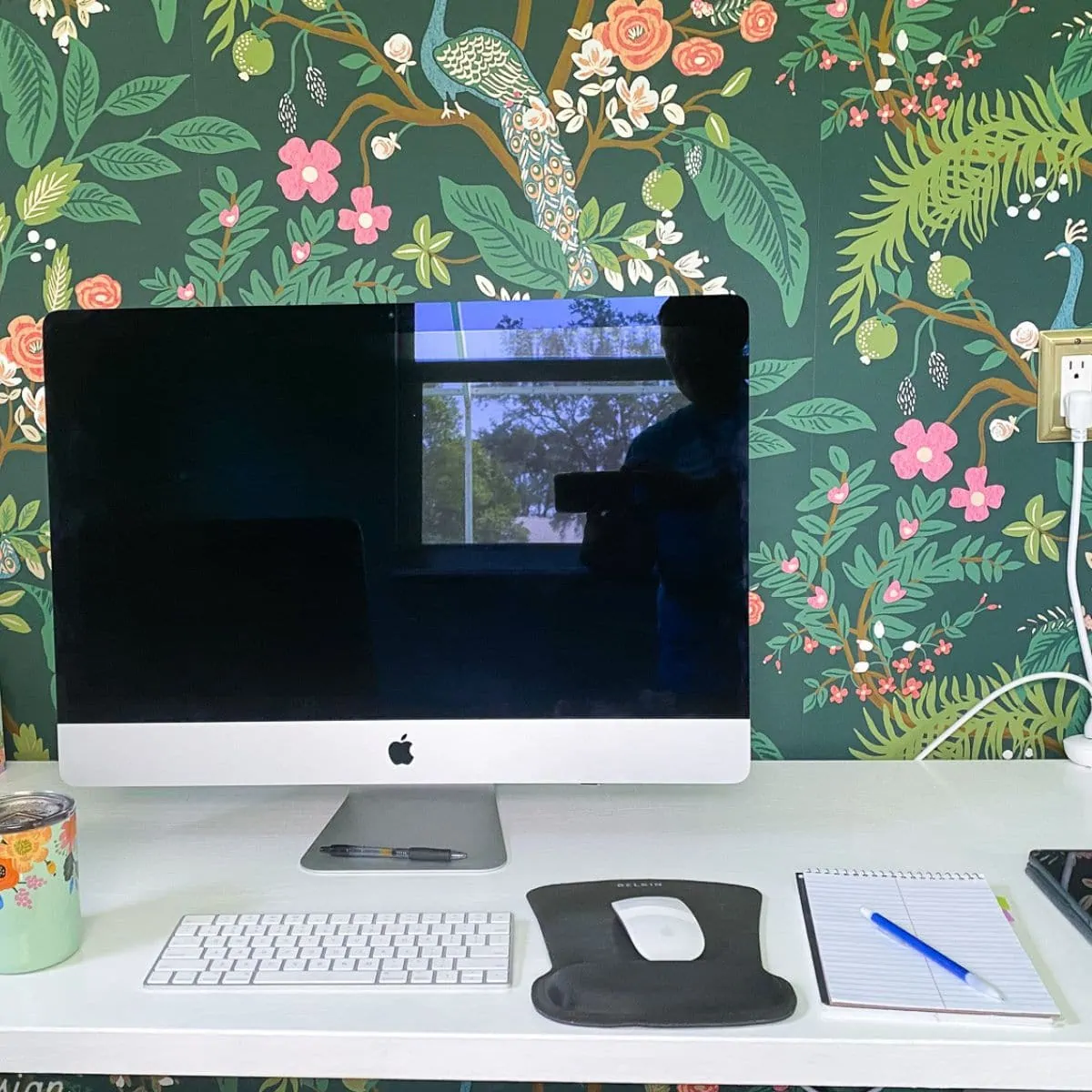 mac desktop with rifle paper co peacock wallpaper on wall behind computer