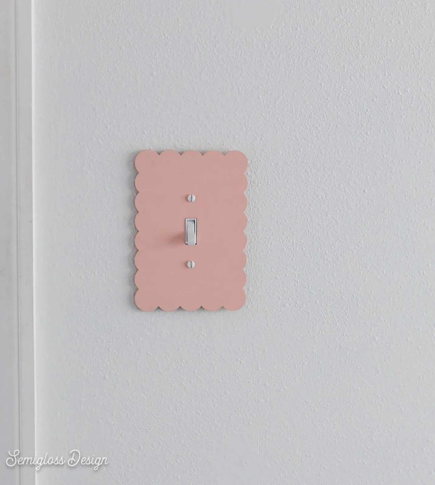 pink scalloped light switch cover installed on white wall