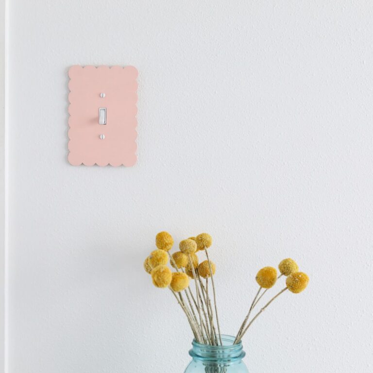 pink scalloped light switch cover and vase of dried flowers