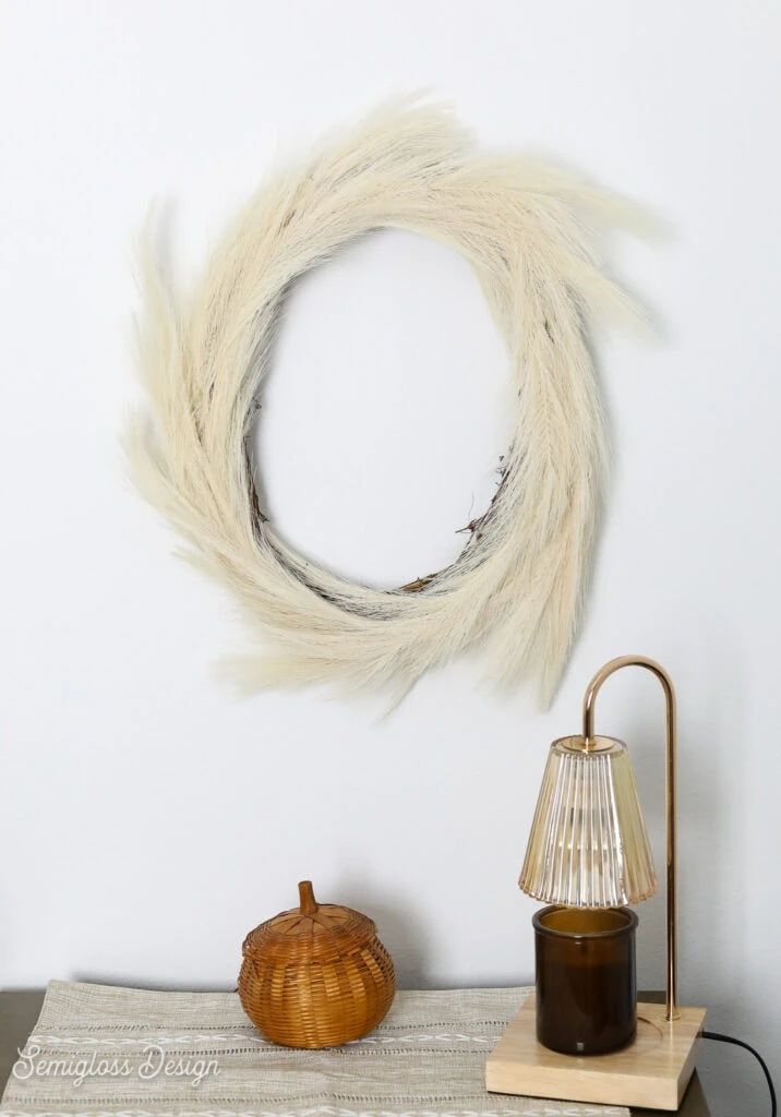 pampas grass wreath, wicker pumpkin and candle lamp on table