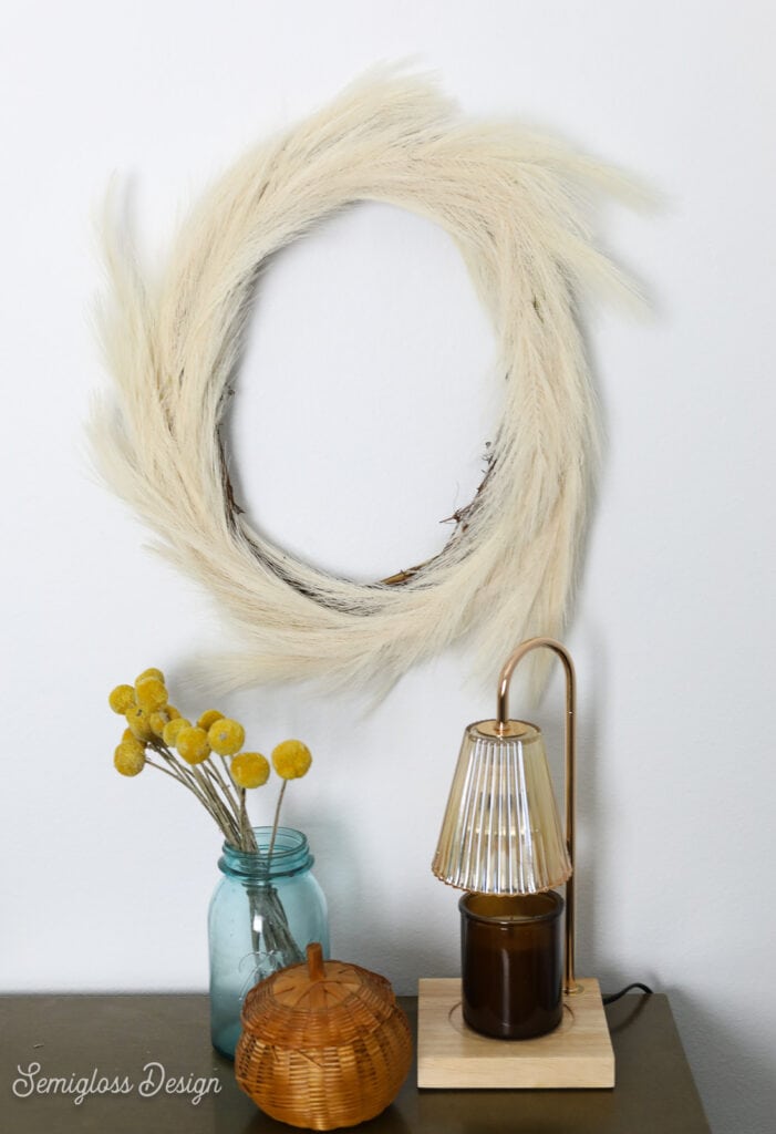pampas grass wreath, vase of billy buttons and candle lamp