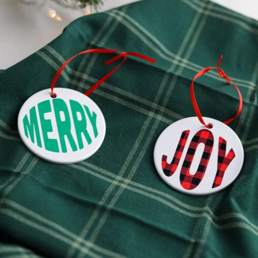 ornaments that say "merry" and "joy" on green plaid napkin