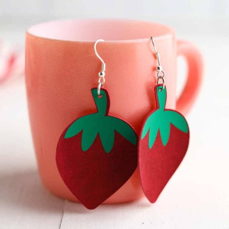 faux leather strawberry earrings on pink mug