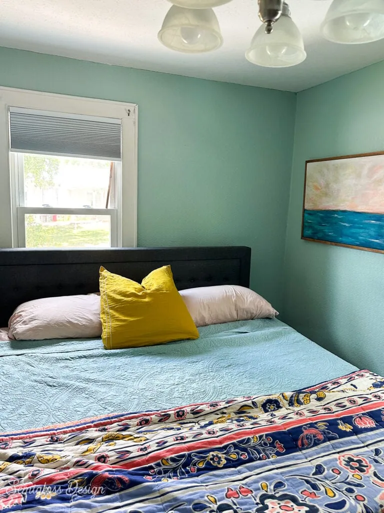 bedroom with aqua walls and colorful bedding