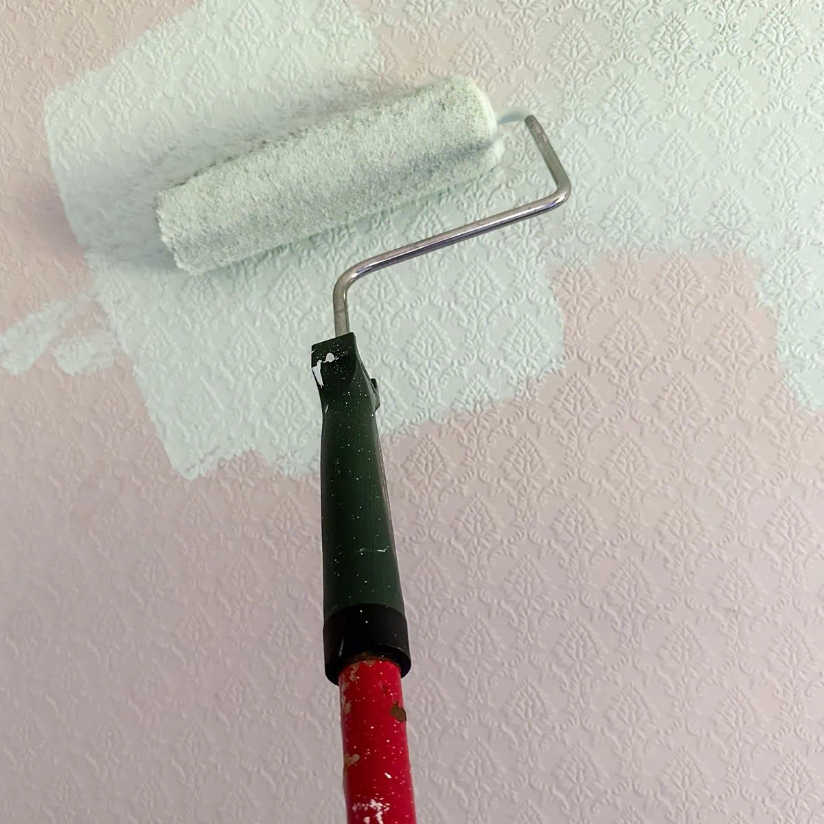 a roller painting a wall teal