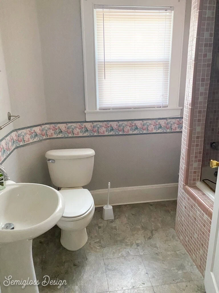 dated bathroom with pink tile and gray walls, floral wallpaper